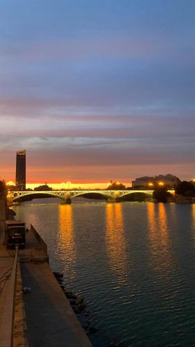 un puente sobre un río por la noche con las luces encendidas en Estudio en el corazón deTriana., en Sevilla