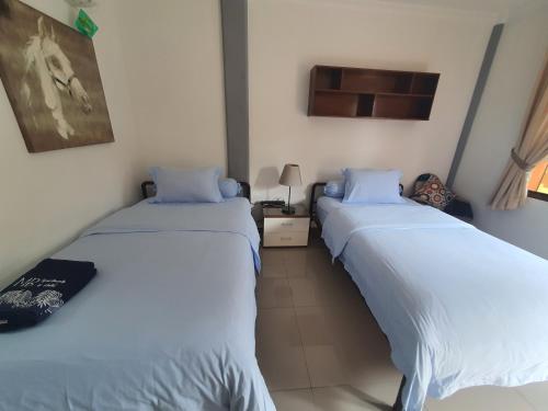 two beds in a room with white sheets at MB Apartments & Hotel Medan in Sunggal