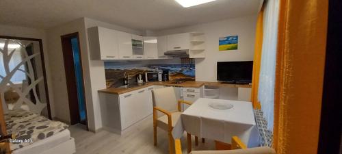 een keuken met een tafel en een kleine keuken met witte kasten bij Appartement auf Rügen in Sagard