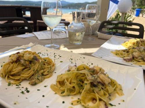 two plates of pasta on a table with wine glasses at Chalet nel Verde di Cavo in Cavo
