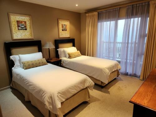 a hotel room with two beds and a window at Villa Penthouse 17-5 in Mossel Bay