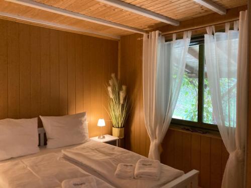 a bedroom with a bed and a window with white curtains at Kantor See-Chalets am Millstätter See in Rothenthurn