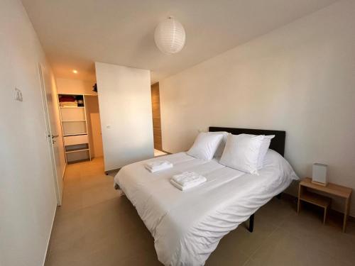 een slaapkamer met een bed met witte lakens en kussens bij L'Eden des Aspres in Thuir