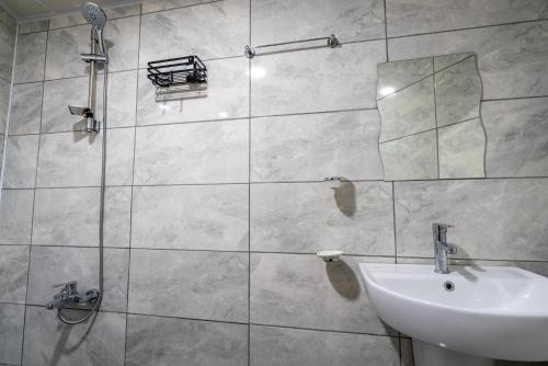 a bathroom with a shower with a sink and a mirror at BÜTÜNOĞLU PANSİYON in Antalya