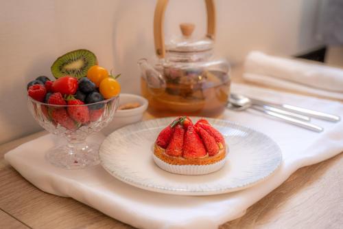 a plate with a strawberry cupcake and a bowl of fruit at GREEN PARK HOTEL PARIS in Paris