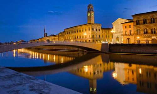 un puente sobre un río con un edificio con una torre de reloj en Sol House, en Pisa