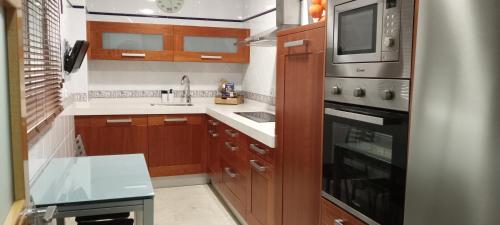 a kitchen with wooden cabinets and a stove top oven at EL RINCÓN DEL GUADALQUIVIR in La Rinconada