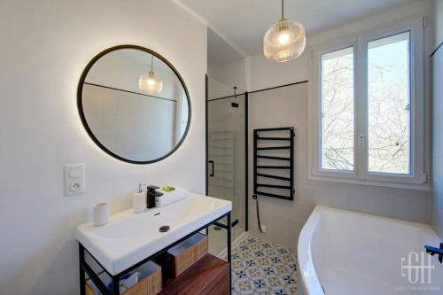 ein Badezimmer mit einer Badewanne, einem Waschbecken und einem Spiegel in der Unterkunft L'élégante/Belle Villa Familiale in Saint-Avertin