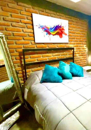 - une chambre avec un lit doté d'oreillers bleus et d'un mur en briques dans l'établissement Cabaña Hermosa Bosque Fraccionamiento Privado, à Mineral del Chico