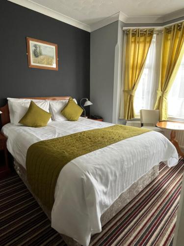 a bedroom with a large bed with yellow curtains at Sorrento Hotel & Restaurant in Cambridge