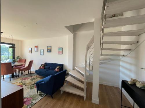 un salon avec un escalier et un canapé bleu dans l'établissement Charmant duplex avec parking, à Gujan-Mestras
