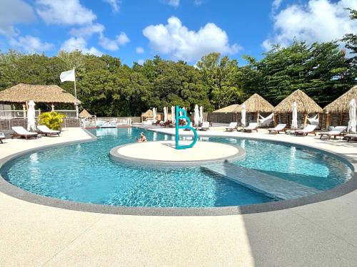 una piscina en un complejo con sillas y sombrillas en La Marigalantine - Piscine, Plage, Blue Dream en Grand-Bourg