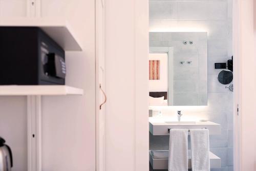 Baño blanco con lavabo y espejo en Woohoo Rooms Boutique Luna en Madrid