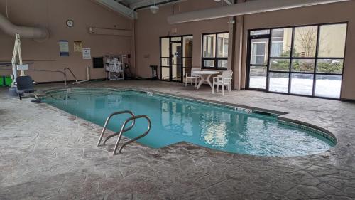 uma grande piscina com uma mesa e cadeiras num edifício em Bangor Suites Airport Hotel em Bangor