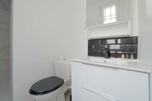 a white bathroom with a black toilet and a sink at Charmant 2 pièces à Issy- les -Moulineaux in Issy-les-Moulineaux