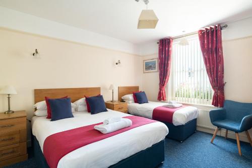 a bedroom with two beds and a blue chair at The Kings Head in Deal