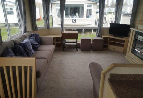 a living room with a couch and a tv at 6 Berth Caravan With Decking At Naze Marine Holiday Park Ref 17071p in Walton-on-the-Naze