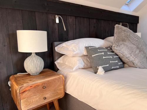 a bed with a wooden headboard and a lamp on a table at Dyfi Hideaway - Holiday Cottage Snowdonia - Stunning River & Valley Views - Ynyshir in Machynlleth