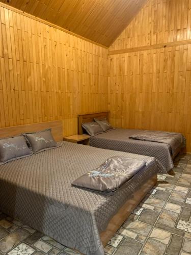 two beds in a room with wooden walls at Mộc House in Kon Tum Kơ Pang