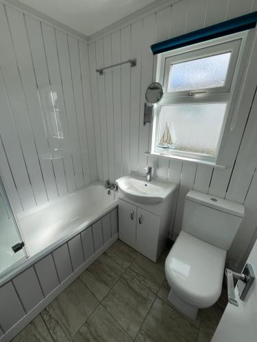 a white bathroom with a toilet and a sink at Chalet 319, Hemsby - Two bed chalet, sleeps 5, pet friendly, bed linen and towels included in Hemsby