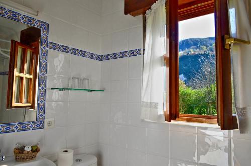 a bathroom with a window and a toilet and a sink at Casa Marian in Cangas de Onís