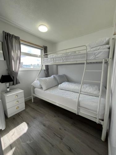 a bedroom with two bunk beds and a window at Chalet 319, Hemsby - Two bed chalet, sleeps 5, pet friendly, bed linen and towels included in Hemsby