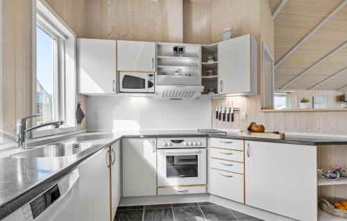 a kitchen with white cabinets and a sink at Holiday Home Sydals 57 With Hot Tub in Skovby