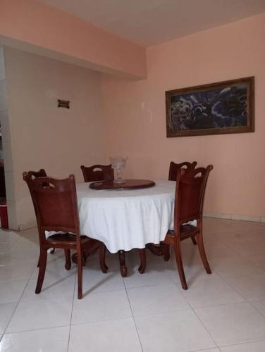 a dining room table with four chairs and a white table cloth at Kaza Mamai di Fora in Calheta