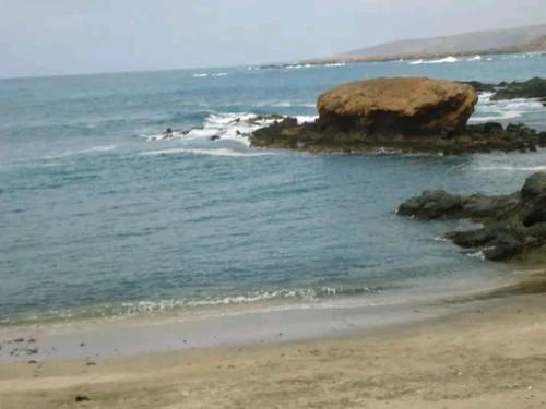 a beach with a large rock in the water at Kaza Mamai di Fora in Calheta de São Miguel