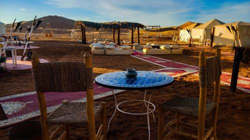 a table and chairs and tents in the desert at Horaz Merzouga Camp in Merzouga