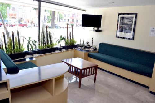 a waiting room with a couch and a table and a tv at Hotel Arizona in Mexico City