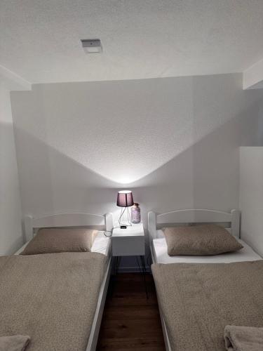 a room with two beds and a table with a lamp at Lena 2 in Jajce
