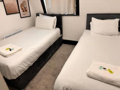 2 bedden in een kleine kamer met witte lakens bij Ivy House Hotel in Londen