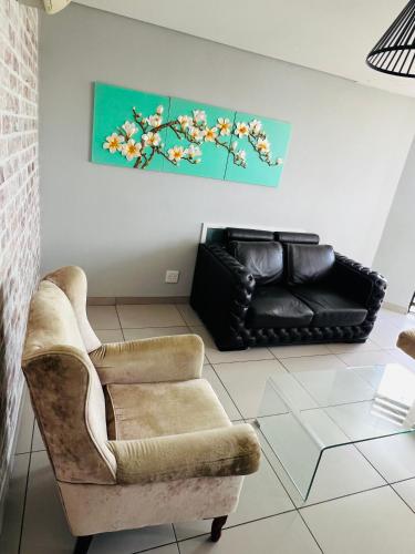 een woonkamer met een bank en een stoel bij Wild olive Self catering in Windhoek
