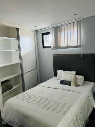 een slaapkamer met een groot bed met witte lakens bij Wild olive Self catering in Windhoek
