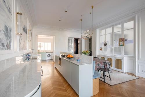 - une cuisine avec des murs blancs et une grande île blanche dans l'établissement Veeve - Enlightened Elegance, à Paris