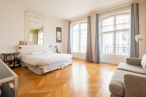 - une chambre avec un lit, 2 fenêtres et un canapé dans l'établissement Veeve - Enlightened Elegance, à Paris
