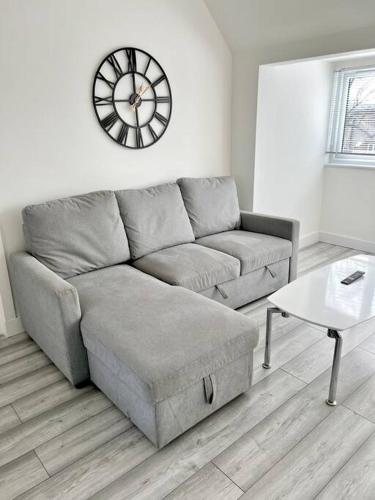 a living room with a couch and a clock on the wall at Luton flat with parking in Luton