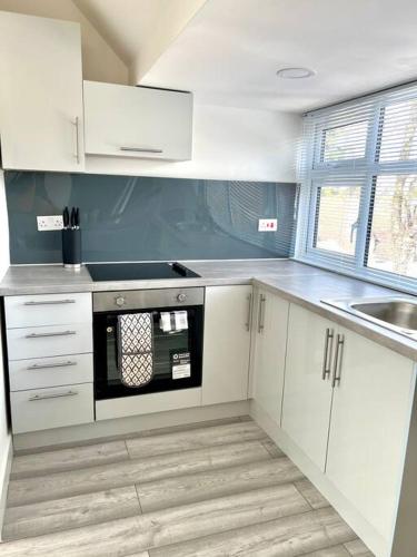 a kitchen with white cabinets and a black microwave at Luton flat with parking in Luton