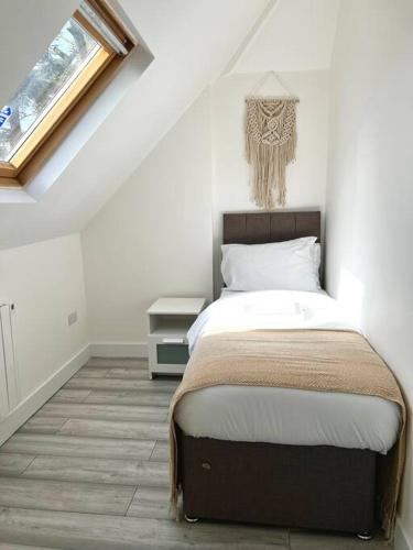 a bedroom with a bed and a window in a attic at Luton flat with parking in Luton