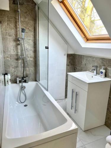 uma casa de banho com uma grande banheira branca e um lavatório. em Luton flat with parking em Luton
