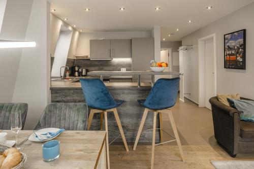 a living room with two blue chairs and a kitchen at Beach House Penthousewohnung Düne in Timmendorfer Strand