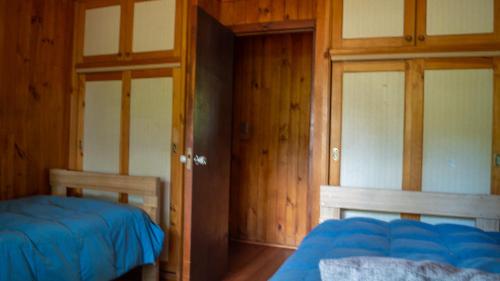 a bedroom with two beds and wooden walls at Casa Dalpa Pucón in Pucón