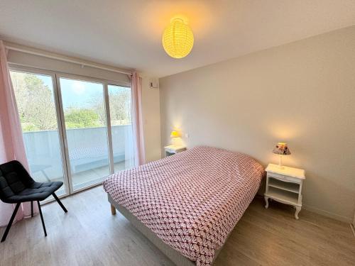 1 dormitorio con 1 cama, 1 silla y 1 ventana en Bel appartement T3 de standing – proche de la mer, en Plouharnel