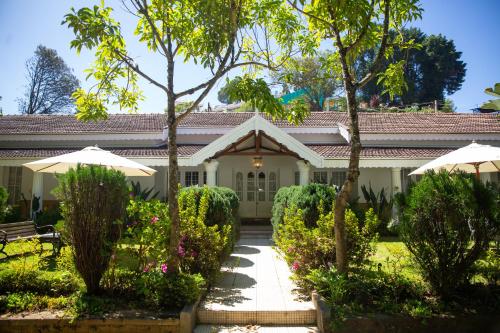 una casa con due ombrelloni in un giardino di Marlihill Bungalow - A CGH Earth SAHA Experience a Ooty