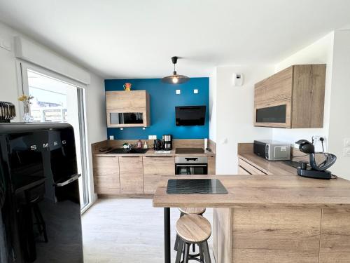 cocina con nevera negra y armarios de madera en Bel appartement T3 de standing – proche de la mer, en Plouharnel