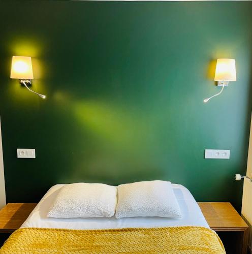 a bedroom with a green wall and a bed with two lamps at Restaurant Hotel Logis Chez Sophie in Briouze