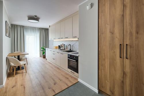 a kitchen with white cabinets and a table and a kitchen with a stove at Symphony City Square Aparthotel in Wrocław