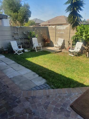 two white chairs sitting in a yard with grass at Ludinz guest house in Cape Town