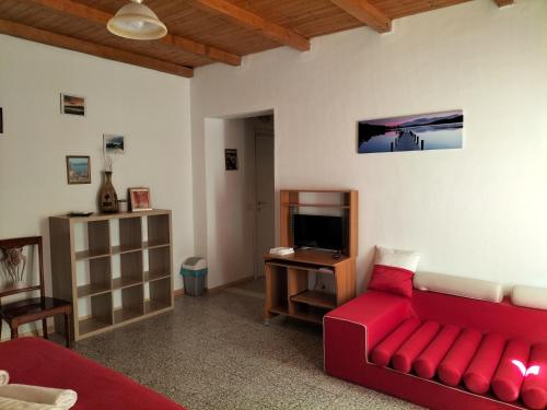 een woonkamer met een rode bank en een tv bij The square in Orosei